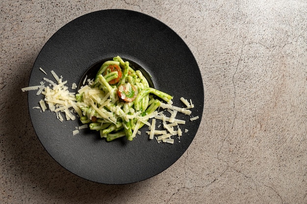 Vista dall'alto di Troffi al pesto con parmessano un piatto tradizionale italiano su uno sfondo di cemento.