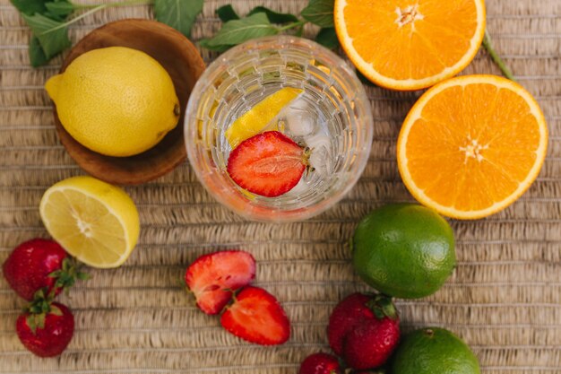 Vista dall'alto di un bicchiere alto con ghiaccio d'acqua e fette di fragola frutta fresca sul tavolo all'aperto lime