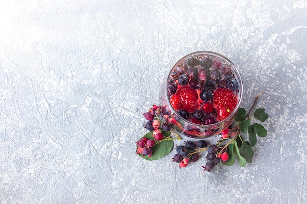 Vista dall'alto di un bicchiere di bevanda detox con frutti di bosco e limone su sfondo di cemento