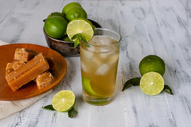 Vista dall'alto di un bicchiere di bevanda fredda panela o acqua di canna da zucchero con limone e ghiaccio fresco fatto in casa su un tavolo di legno invecchiato