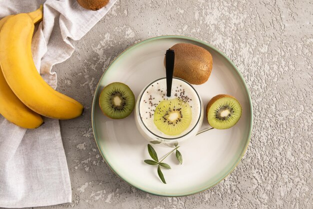 Vista dall'alto di un bicchiere di frullato a base di kiwi e banana con semi di chia delizioso dessert sano fonte di fibra alimentare sfondo grigio cemento