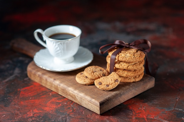 Vista dall'alto di un delizioso caffè in una tazza bianca e biscotti di zucchero fatti in casa su una tavola di legno marrone su sfondo di colori misti scuri con spazio libero