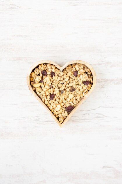 Vista dall'alto di un fiocco a forma di cuore pieno di muesli croccante. Mangiare sano concetto.