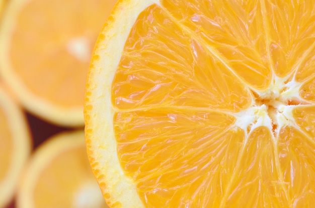 Vista dall&#39;alto di un frammento della fetta di frutta arancione sullo sfondo di molte fette di arancia offuscata.