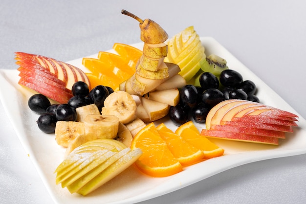 Vista dall'alto di un'insalata di frutta con fragole, arance, kiwi, mirtilli e pesche. Concetto di intaglio di frutta