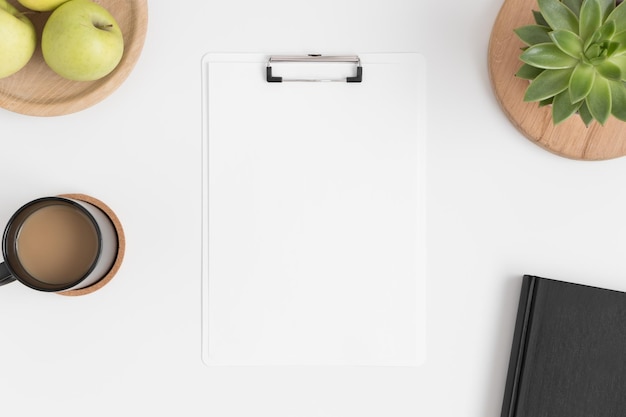 Vista dall'alto di un mockup di appunti bianco con una pianta succulenta di mele e un caffè su un tavolo bianco