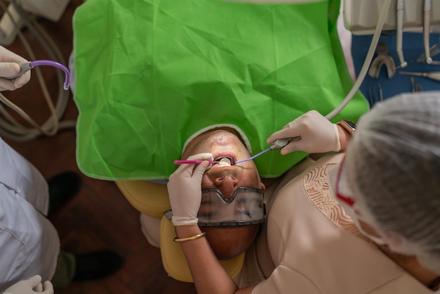 Vista dall'alto di un paziente sdraiato su una barella dentale mentre un dentista sta lavorando