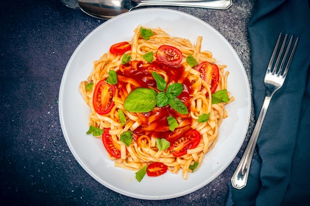 Vista dall'alto di un piatto di spaghetti con una deliziosa salsa di pomodoro fatta in casa con foglie di basilico