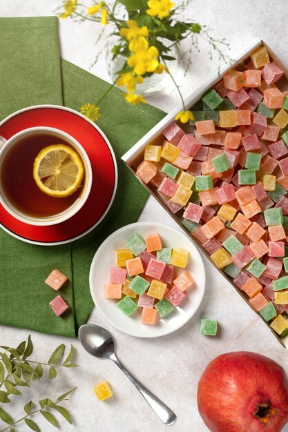 Vista dall'alto di un tea party una tazza di tè e una scatola con dolci a forma di cubetti di marmellata multicolori