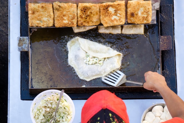 Vista dall'alto di un uomo che cucina le verdure martabak jawa nella città di Kota Kinabalu durante il ramadan