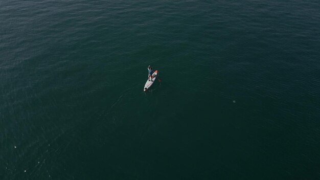 Vista dall'alto di un uomo che rema su un paddleboard standup o su una tavola SUP su un mare calmo