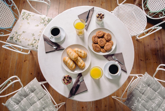 Vista dall'alto di una deliziosa e sana colazione con succo d'arancia, yogurt e caffè serviti su un tavolo pronto da mangiare