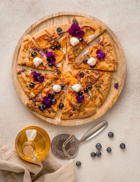 Vista dall'alto di una deliziosa fetta di pizza con mirtilli e petali di fiori