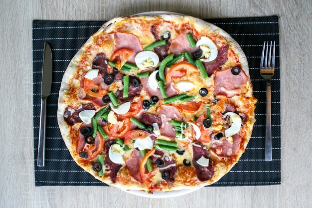 Vista dall'alto di una deliziosa pizza fresca con fagioli, formaggio, prosciutto e uova