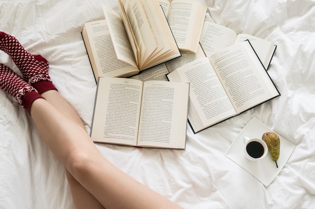 Vista dall&#39;alto di una donna che legge libri sul copriletto bianco