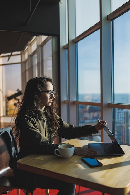 Vista dall'alto di una donna esperta in occhiali che lavora con il computer portatile nello spazio di coworking giovane libero professionista che lavora a distanza con idee per il sito web del blog