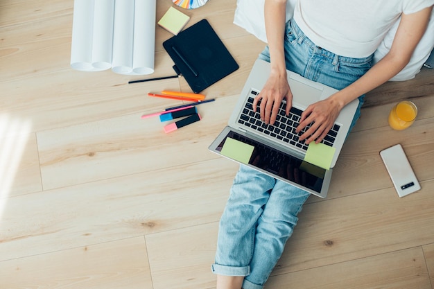 Vista dall'alto di una donna in abiti casual seduta sul pavimento con un laptop e digitando sulla tastiera Banner del sito web