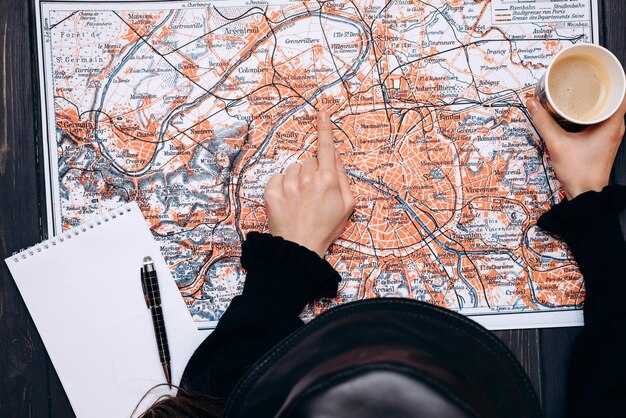 Vista dall'alto di una fanciulla che indica una mappa con un caffè in mano Concetto di pianificazione del viaggio