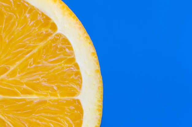 Vista dall&#39;alto di una fetta di frutta arancione su sfondo luminoso in colore blu. Un&#39;immagine di trama di agrumi saturi