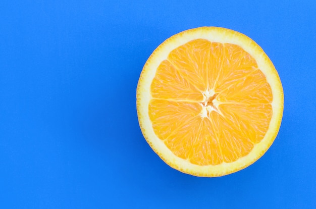 Vista dall&#39;alto di una fetta di frutta arancione su sfondo luminoso in colore blu