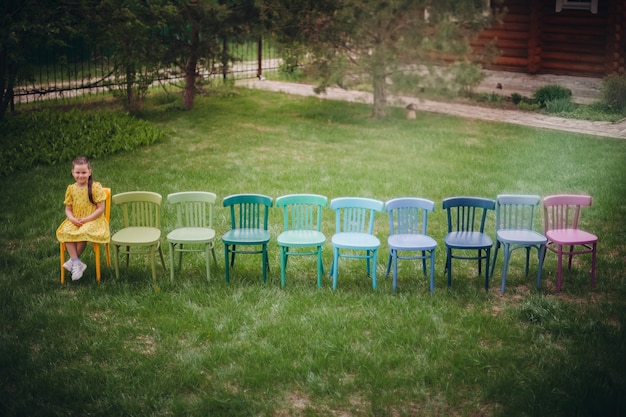 Vista dall'alto di una fila di sedie in legno colorate per una cerimonia di matrimonio nel parco su un prato verde su...