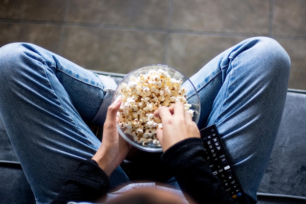 Vista dall'alto di una persona che mangia popcorn guardando la TV