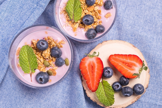 Vista dall'alto di una sana colazione a base di mirtilli, fragole e cereali con yogurt cremoso