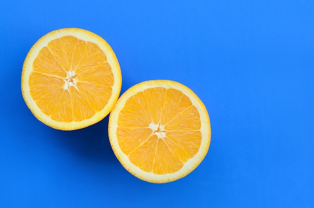 Vista dall&#39;alto di una serie di fette di frutta arancione su sfondo luminoso in colore blu.