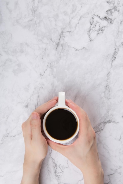 vista dall'alto di una tazza di caffè nero tenuta per mano