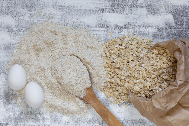 Vista dall'alto di uova di avena e farina di avena su sfondo bianco