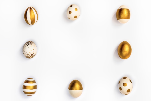 Vista dall'alto di uova di Pasqua colorate con vernice dorata disposte in quadrato. Sfondo bianco. Copia spazio.
