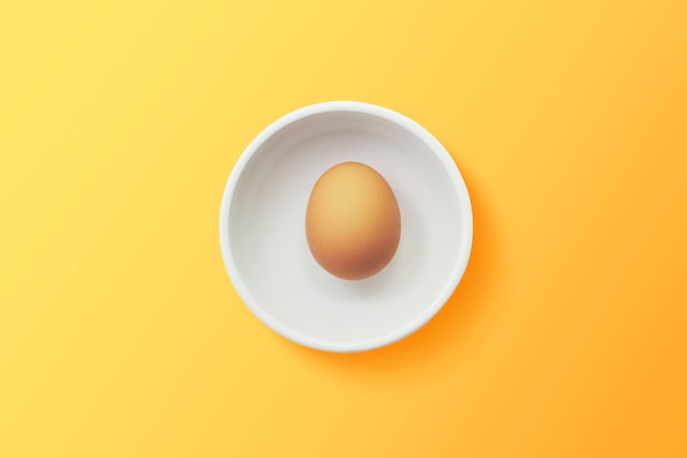 Vista dall'alto di uovo in una ciotola su sfondo arancione