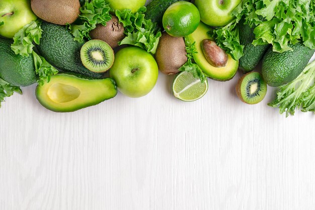 Vista dall'alto di varie verdure e frutta verdi su fondo in legno bianco con spazio per la copia