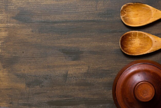 Vista dall'alto di vaso di terracotta e cucchiai di legno sullo sfondo di legno con spazio per la copia