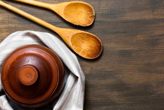 Vista dall'alto di vaso di terracotta e cucchiai di legno sullo sfondo di legno con spazio per la copia