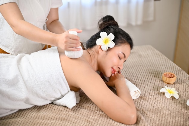 Vista dall'alto Donna asiatica sdraiata sul lettino da massaggio che riceve un massaggio del corpo con una palla a base di erbe termali