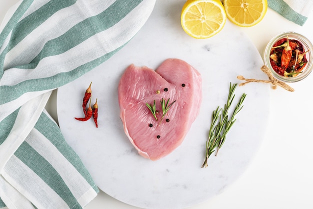 Vista dall'alto filetto di tacchino o pollo con spezie e fette di limone sul bordo di marmo, cucinare a casa concetto