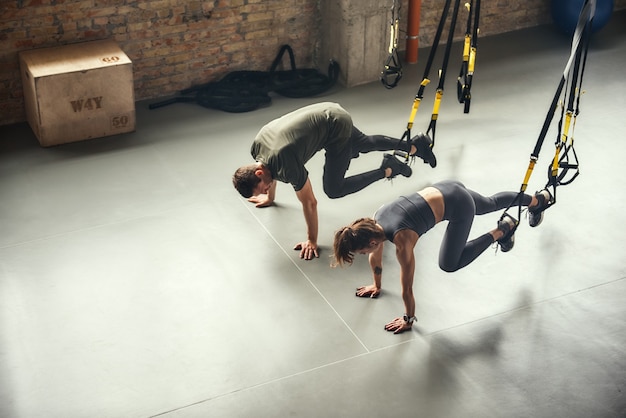 Vista dall'alto giovane e sportiva di una coppia in allenamento sportivo con cinturini fitness trx