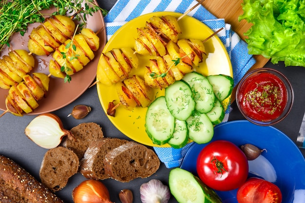 Vista dall'alto: griglia kebab di patate con pancetta a bastoncini di legno. Ingredienti. Verdure