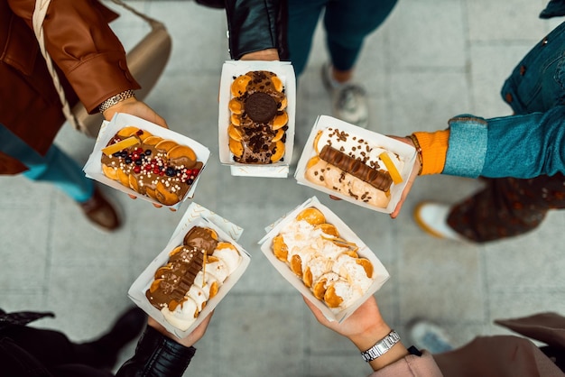 Vista dall'alto gruppo fotografico di amici nelle loro mani che tengono freschi deliziosi poffertjes. Foto di alta qualità