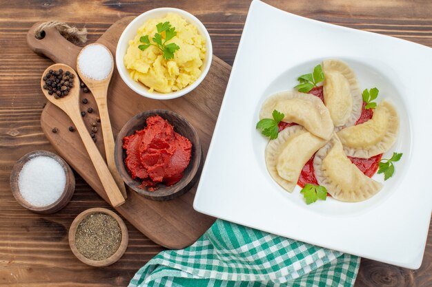 vista dall'alto hotcakes di patate con concentrato di pomodoro e condimenti su sfondo marrone cuocere ristorante pasta pasta cucina torte gnocchi