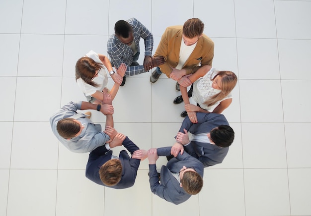 Vista dall'alto il team aziendale si tiene per mano il concetto di team building