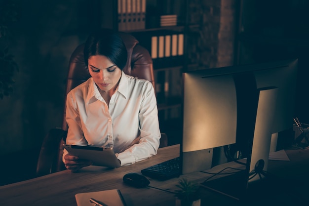 Vista dall'alto in alto di bella attraente elegante intelligente intelligente abile signora finanziere economista utilizzando e-book digitale analisi rapporto piano reddito profitto investire tasso notte buio posto di lavoro stazione