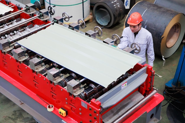 Vista dall'alto Ingegnere di fabbrica che aziona la macchina del tetto in lamiera presso la produzione di industria pesante Operaio in elmetto protettivo di sicurezza presso le strutture industriali della fabbrica