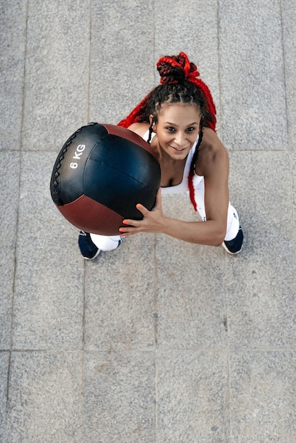 Vista dall'alto La donna atletica lancia la palla erumata Forza e motivazione Foto di una donna sportiva in abbigliamento sportivo alla moda