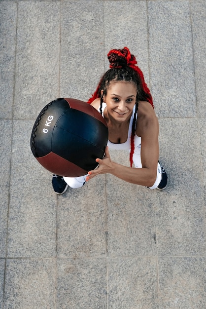 Vista dall'alto. La donna atletica lancia la palla med. Forza e motivazione Foto di donna sportiva in abbigliamento sportivo alla moda