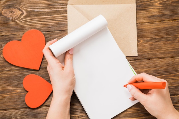 Vista dall'alto Mano della ragazza che scrive una lettera d'amore il giorno di San Valentino