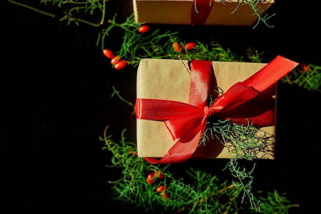 Vista dall'alto Natale imballaggio ecologico carta kraft e rami di abete regali per le festività natalizie su sfondo nero