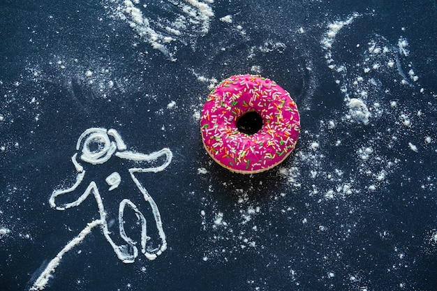 Vista dall'alto piatto laici natura morta creativa con ciambella rosa e astronauta fatto con farina sul nero