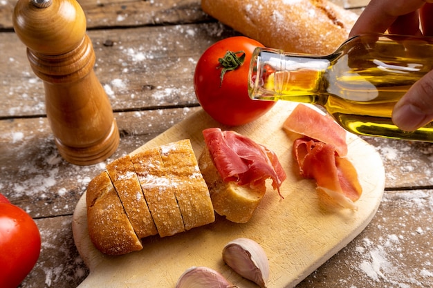 vista dall'alto prosciutto, pane e pomodori sulla tavola di legno